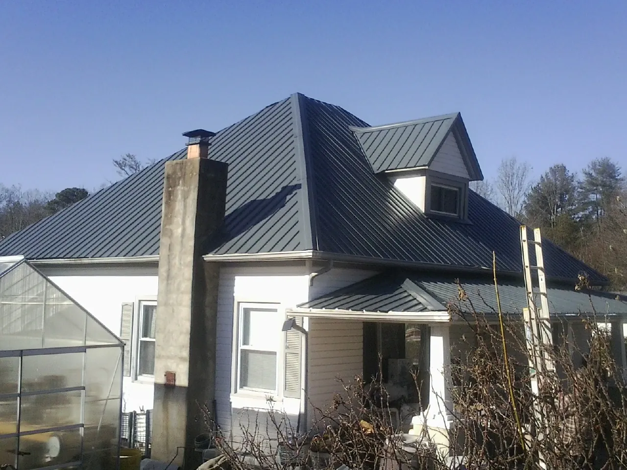 Dark blue standing seam metal roof on a white farmhouse with dormer — Slate & Tile Roof Repair by Roofing Brothers in Summer Lake