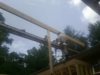 Carpenter setting a ridge beam over a new addition frame — Ice Dam Removal by Roofing Brothers in Summer Lake
