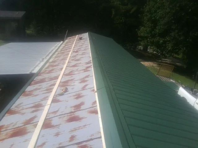 Old rusted panels beside newly installed green metal roofing — Wind Damage Roof Repair by Roofing Brothers in Summer Lake