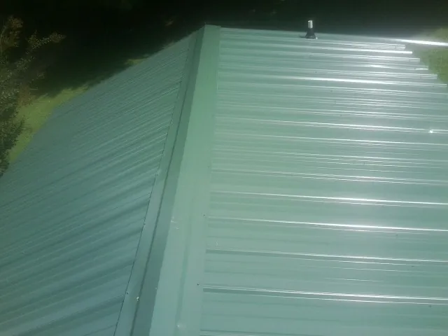 New green metal panels meeting at the ridge of a roof — Flat Roof Repair work by our crew in Summer Lake
