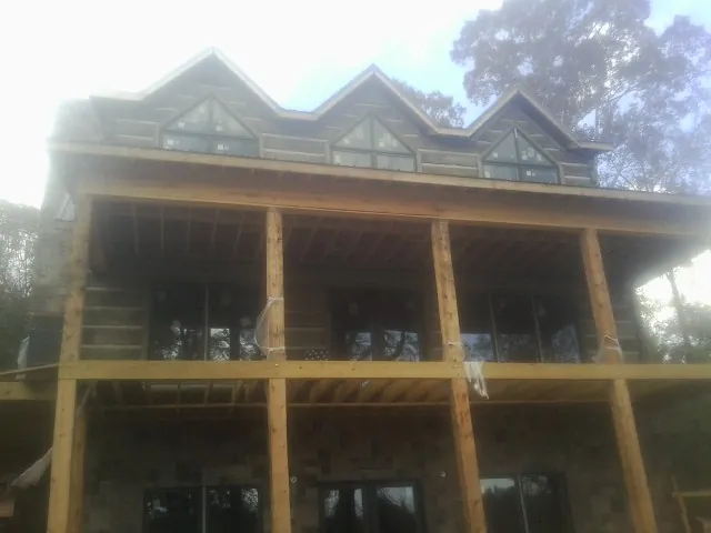 Dormers and porch framing on a large log home under construction — Roof Coating work by our crew in Summer Lake