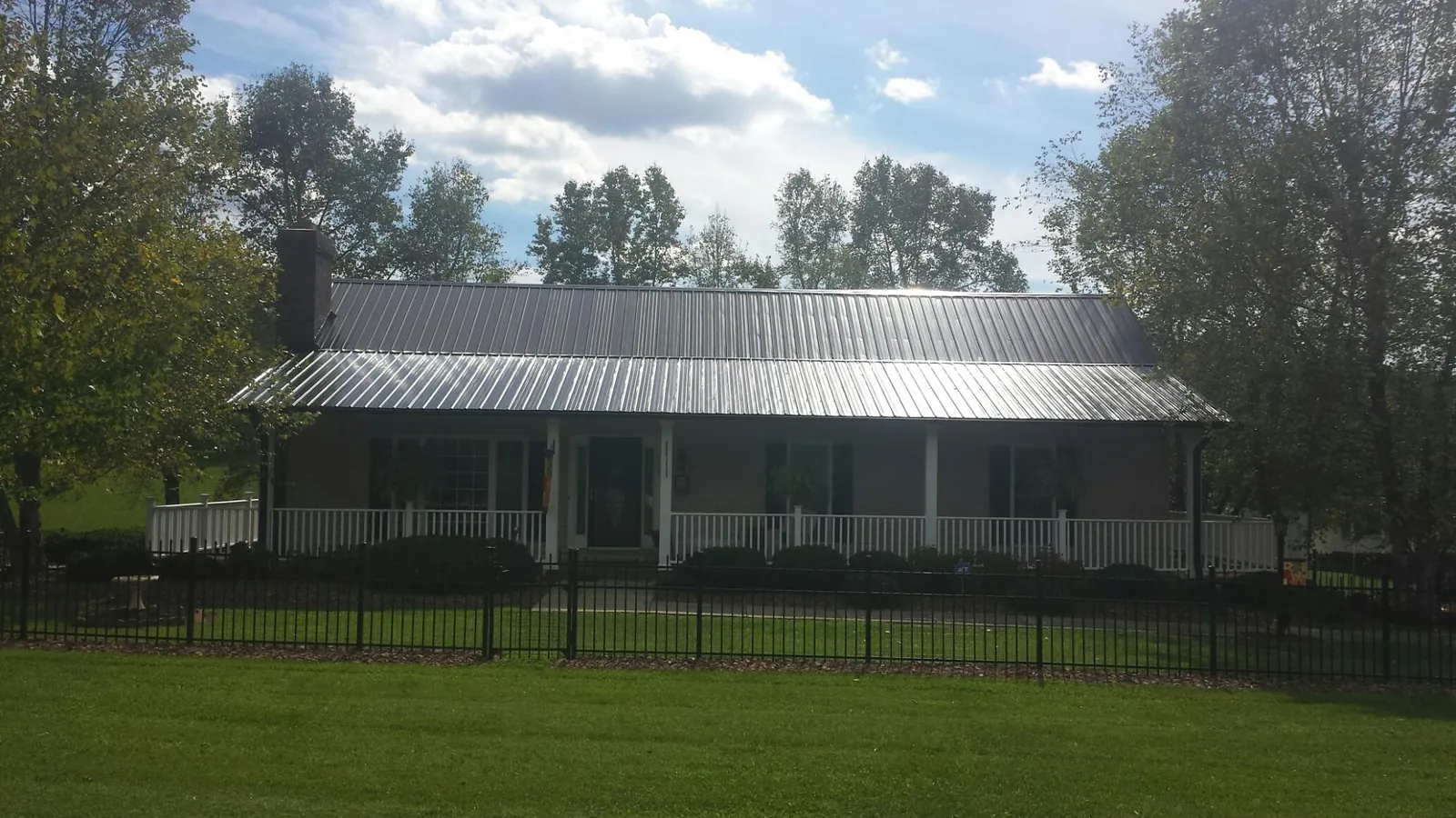 Gray metal roof on a brick ranch with a full width front porch — Gutter Guard Installation work by our crew in Summer Lake