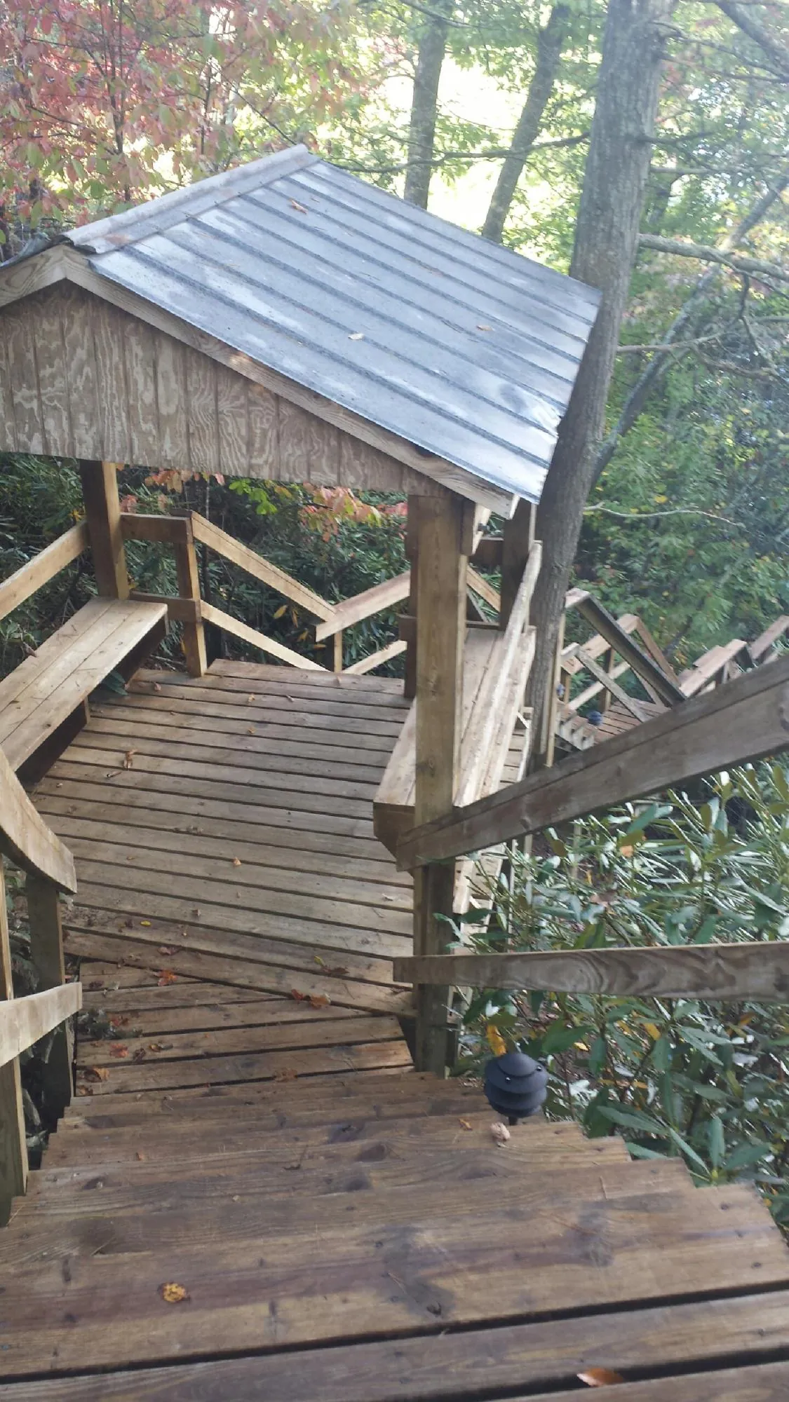 Metal roofed shelter over wooden steps on a wooded walkway — Skylight Repair & Installation work by our crew in Summer Lake