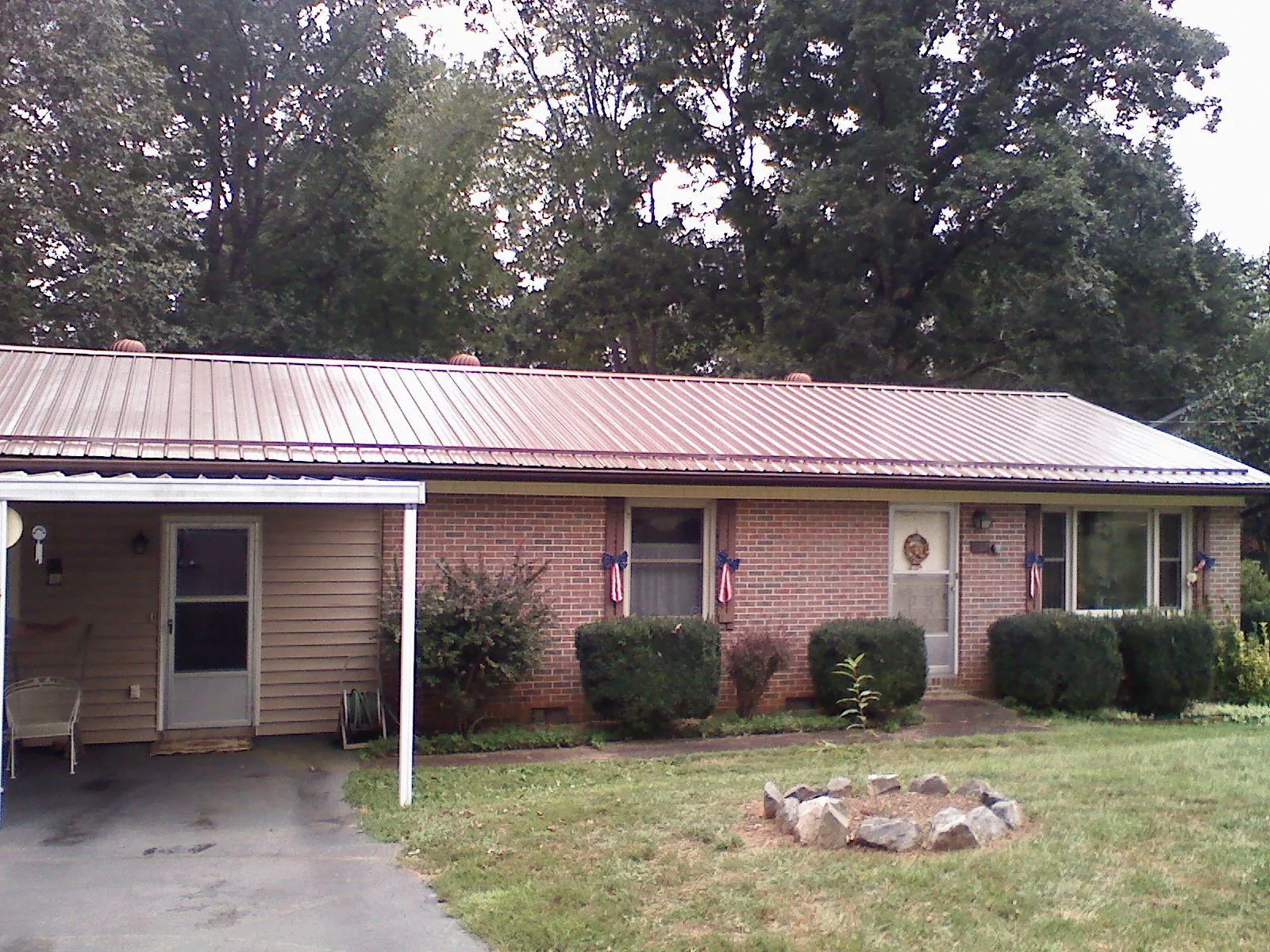 Bronze metal roof and carport on a brick ranch home — Roof Repair work by our crew in Summer Lake