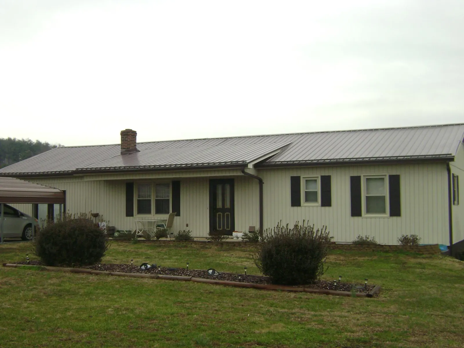 Brown metal roof on a cream sided ranch home with a brick chimney in Summer Lake