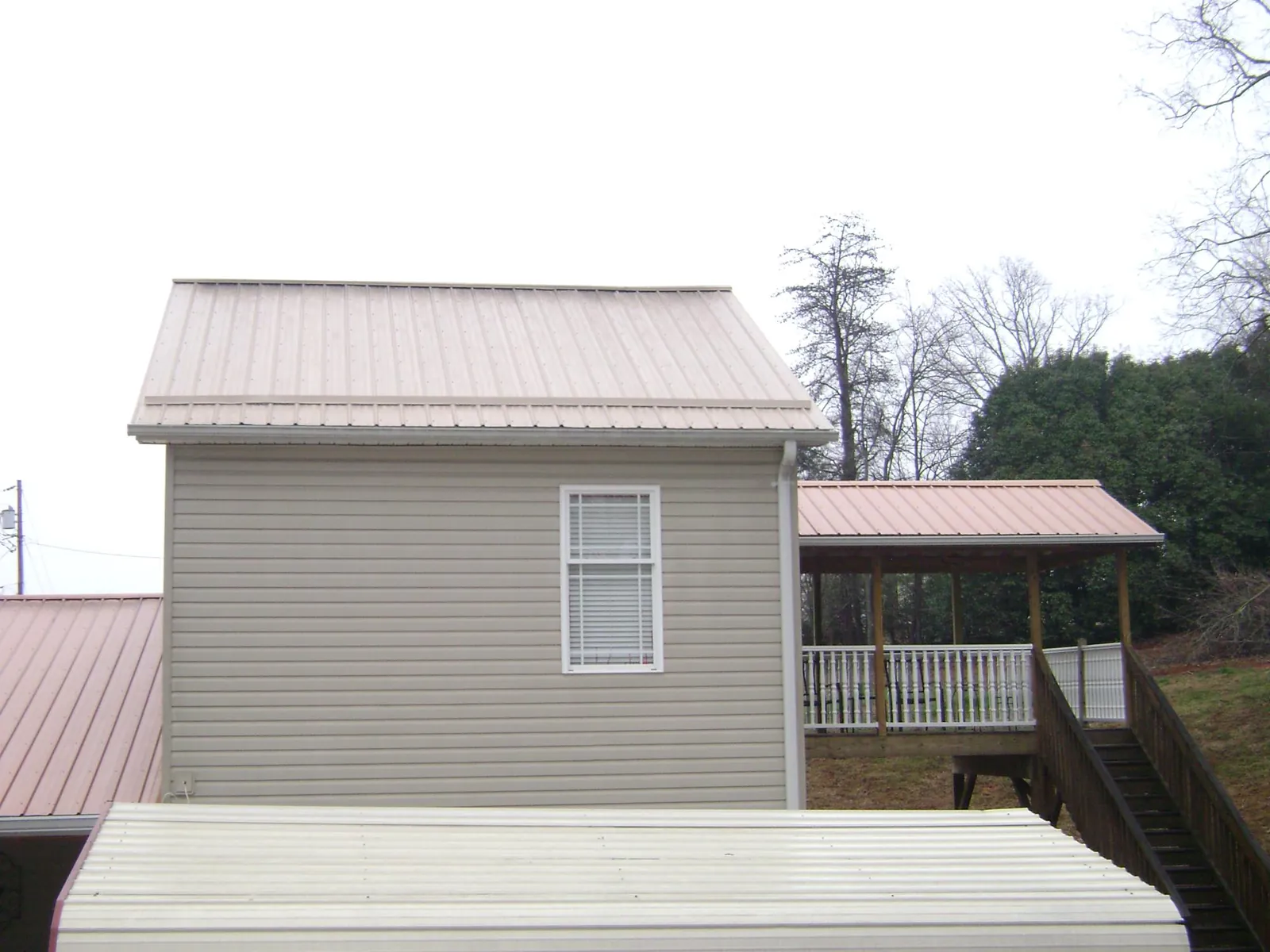 Tan metal roofs on a two story addition and attached porch, from a Roof Replacement job in Summer Lake