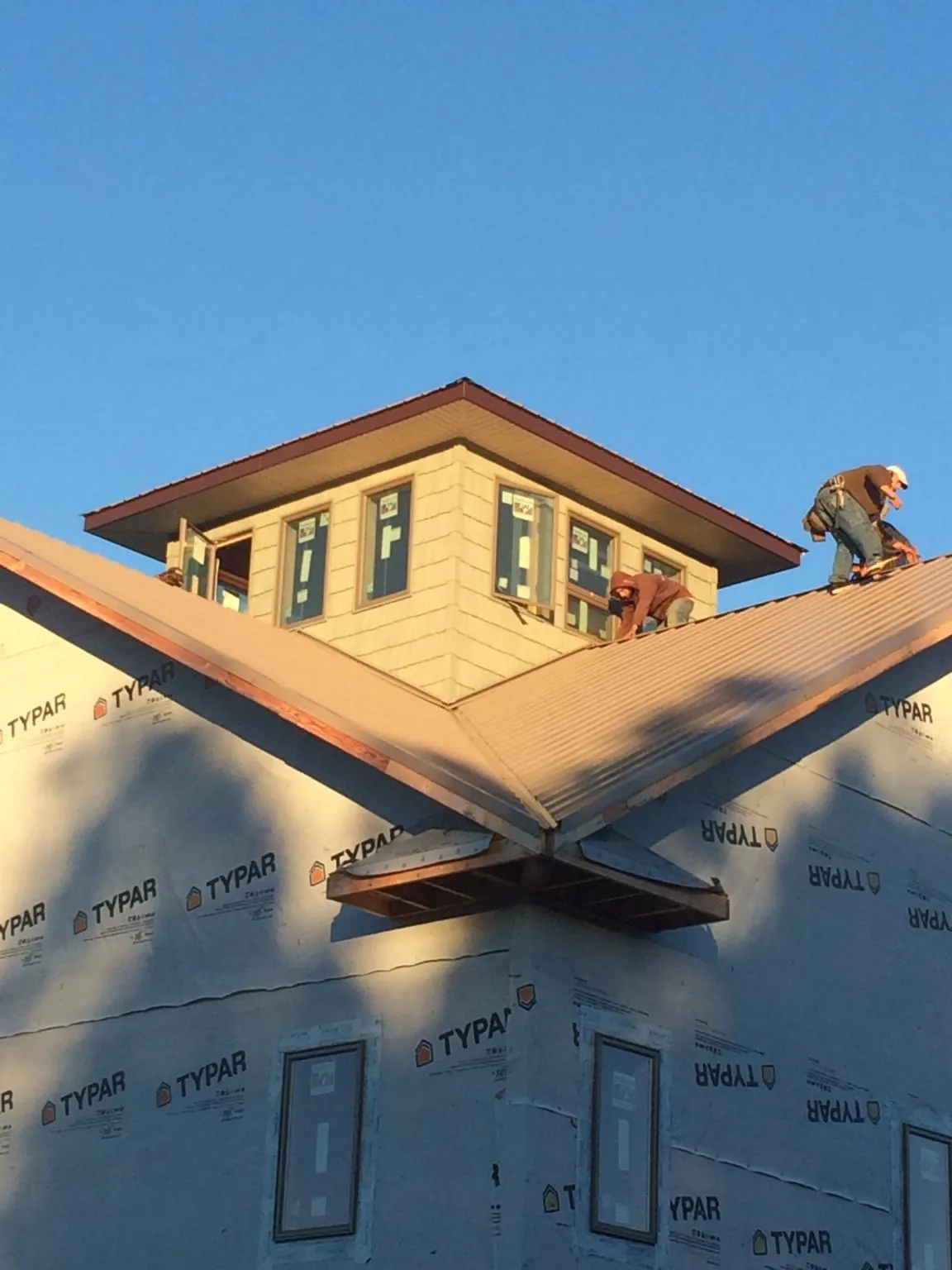 Roofers working around a rooftop cupola on a new metal roof at sunset — Roof Waterproofing in Summer Lake by Roofing Brothers